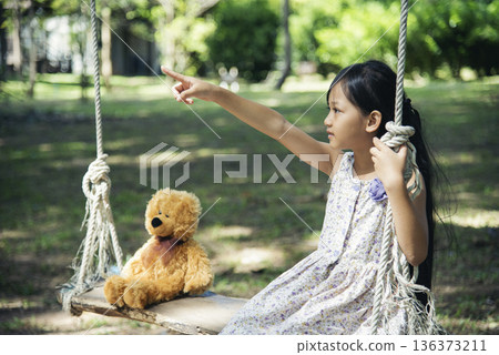 Happy Child hug teddy bear in green park playground. Teddy bear best friend for little kids cute girl. Autism happy funny playing together on playground in happiness family feel love and warm hugs 136373211