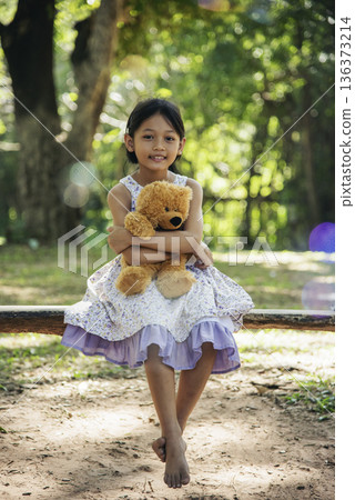Happy Child hug teddy bear in green park playground. Teddy bear best friend for little kids cute girl. Autism happy funny playing together on playground in happiness family feel love and warm hugs 136373214