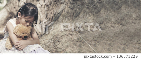 Banner Happy Child hug teddy bear in green park playground. Teddy bear best friend for little girl. Autism happy playing together on playground in happiness family feel love warm hugs with copy space 136373229