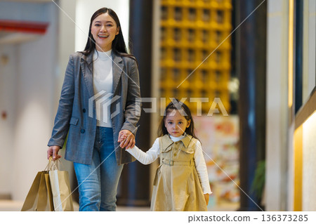 mother and child girl walking with shopping bag in a department store mother and child girl walking with shopping bag in a department store 136373285
