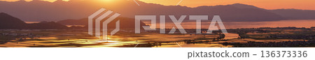 從滋賀縣東近江市豬子町的豬子山上眺望，傍晚時分，稻田在播種前的夕陽映照下泛著橙紅的光芒。 136373336