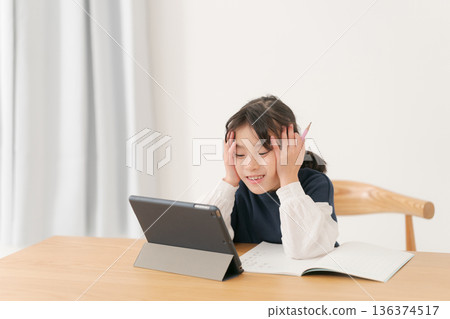 Elementary school girl studying on a tablet Elementary school girl studying on a tablet 136374517