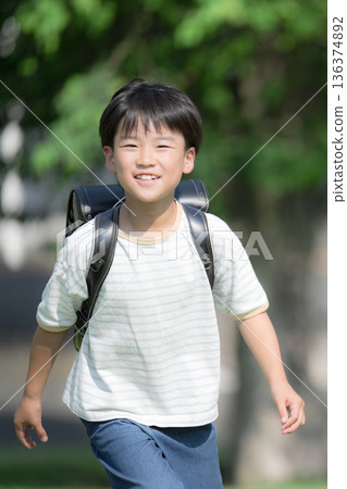 一個男孩背著書包奔跑，看著鏡頭。 136374892