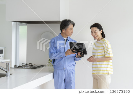 一位中年婦女正在聽一位承包商用平板電腦講解一些東西。 136375190