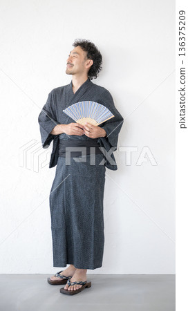 Full body of a bearded middle-aged man wearing a yukata against a white background, leaning against a wall and looking up Full body of a bearded middle-aged man wearing a yukata against a white background, leaning against a wall and looking up 136375209