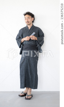 Full body of a middle-aged man with a beard wearing a yukata on a white background, leaning against a wall and looking at the camera Full body of a middle-aged man with a beard wearing a yukata on a white background, leaning against a wall and looking at the camera 136375210