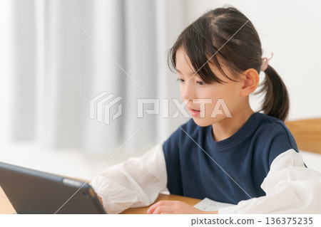 Elementary school girl studying on a tablet Elementary school girl studying on a tablet 136375235