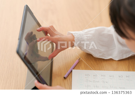 Elementary school girl studying on a tablet Elementary school girl studying on a tablet 136375363