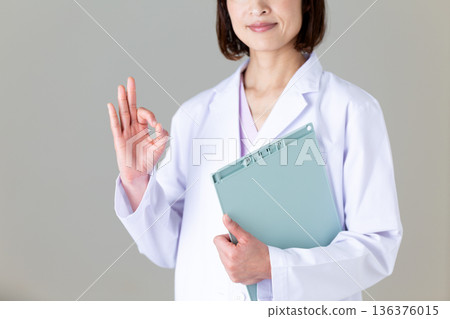 一位身穿白大褂的中年女護士做了一個圓圈手勢 136376015