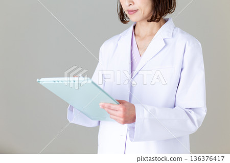 Middle-aged female nurse in a white coat Middle-aged female nurse in a white coat 136376417