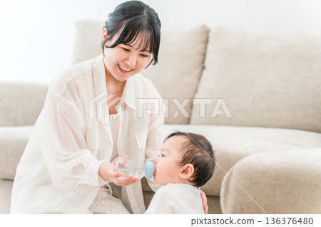 母親在家裡的客廳用奶瓶餵寶寶水。 136376480