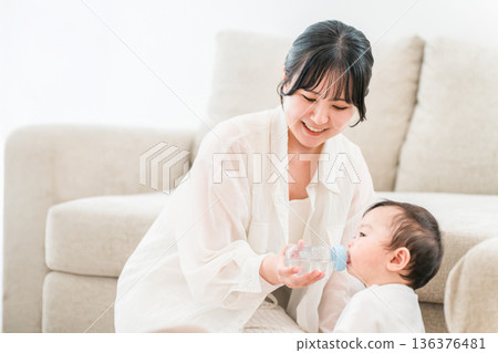 母親在家裡的客廳用奶瓶餵寶寶水。 136376481
