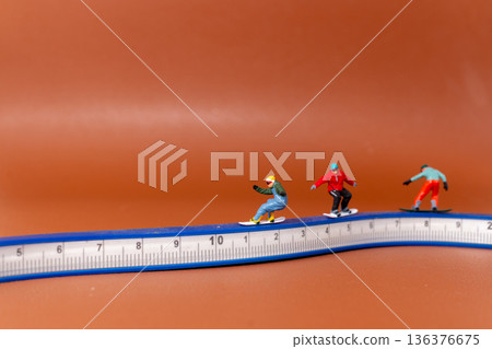 Miniature Snowboarders Riding on Measuring Tape 136376675