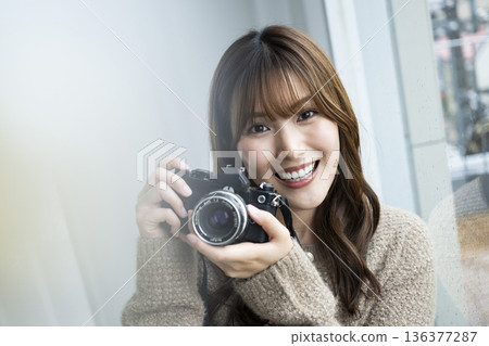 Young woman taking a photo with a SLR camera 136377287