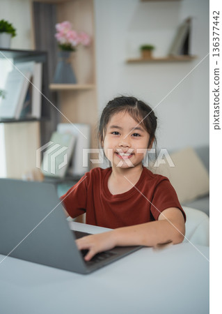 Young girl working on laptop at home, engaging in online learning or creativity, bright and cheerful atmosphere, cozy indoor environment, educational concept Young girl working on laptop at home, engaging in online learning or creativity, bright and cheerful atmosphere, cozy indoor environment, educational concept 136377442