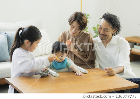 Parents and children relaxing in the living room, baby food 136377773
