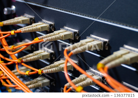 Orange fiber optic cables connected to network switch, showing high speed data transfer, internet connection and modern IT infrastructure 136377815