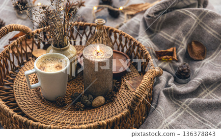 Cozy home composition with a cup of coffee, a candle and decorative details. 136378843