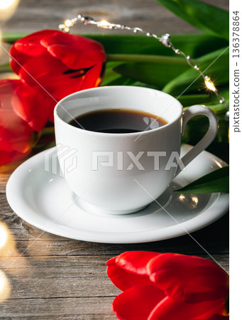 Cup of coffee and red tulips on a wooden surface. Cup of coffee and red tulips on a wooden surface. 136378864