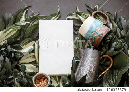 Cup with a teapot on a green leaf background Cup with a teapot on a green leaf background 136378879