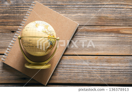 Earth globe and notebook on wooden background, top view. 136378913
