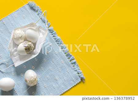 Easter composition with Easter eggs in a protective mask from the coronavirus top view. Easter composition with Easter eggs in a protective mask from the coronavirus top view. 136378952