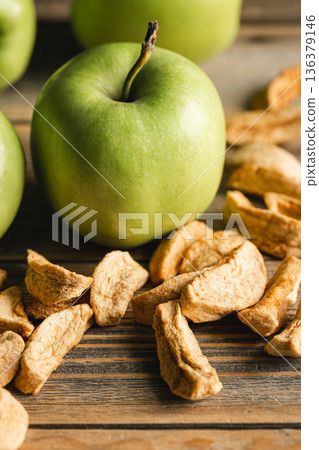 Homemade dried organic apple and and raw green apples on a wood background. Homemade dried organic apple and and raw green apples on a wood background. 136379146