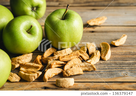 Homemade dried organic apple and and raw green apples on a wood background. Homemade dried organic apple and and raw green apples on a wood background. 136379147