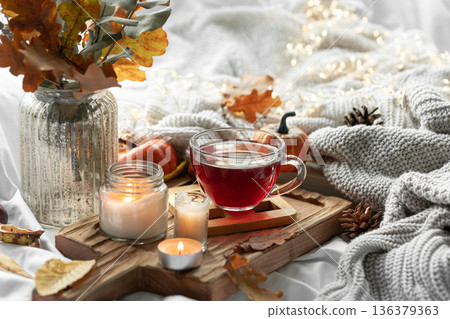 Autumn composition with a cup of tea, leaves and a knitted element. Autumn composition with a cup of tea, leaves and a knitted element. 136379363