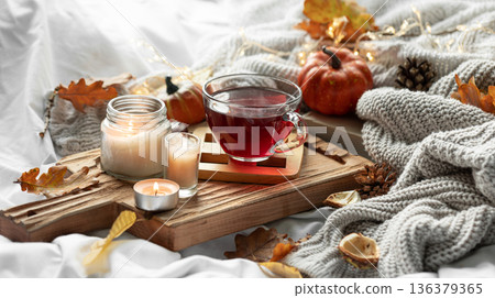 Autumn composition with a cup of tea, leaves and a knitted element. Autumn composition with a cup of tea, leaves and a knitted element. 136379365