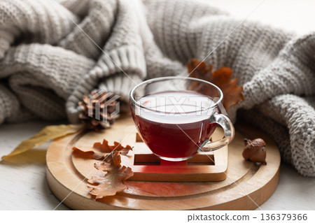 Autumn composition with a cup of tea, leaves and a knitted element. Autumn composition with a cup of tea, leaves and a knitted element. 136379366