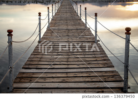 Long wooden pier among the sea at sunset. Long wooden pier among the sea at sunset. 136379450