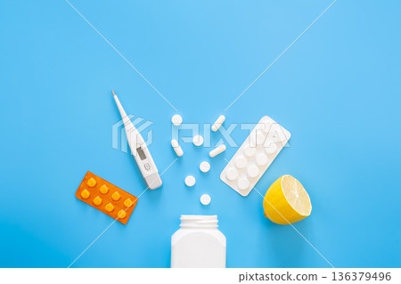 Blue background with pills, thermometer and lemon, flat lay. 136379496