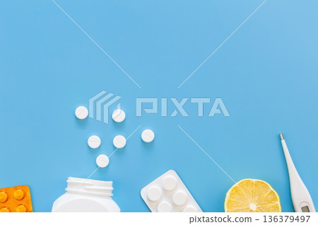 Blue background with pills, thermometer and lemon, flat lay. Blue background with pills, thermometer and lemon, flat lay. 136379497