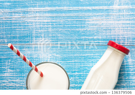Bottle and glass with milk on a blue wooden background, flat lay. Bottle and glass with milk on a blue wooden background, flat lay. 136379506