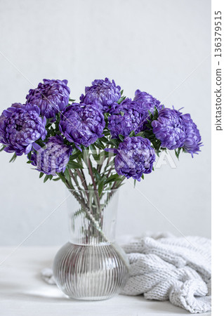 Glass vase with a bouquet of blue chrysanthemums on light background. Glass vase with a bouquet of blue chrysanthemums on light background. 136379515