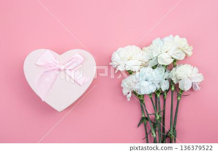A bouquet of flowers, heart shaped gift box on pink background, flat lay. A bouquet of flowers, heart shaped gift box on pink background, flat lay. 136379522
