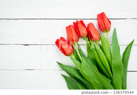 Bouquet of red tulips on a white wooden background, top view. Bouquet of red tulips on a white wooden background, top view. 136379544