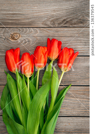 Bouquet of red tulips on a wooden background, top view. Bouquet of red tulips on a wooden background, top view. 136379545