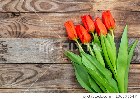 Bouquet of red tulips on a wooden background, top view. Bouquet of red tulips on a wooden background, top view. 136379547