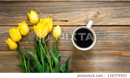 Bouquet of yellow tulips and cup of coffee on a wooden background, top view. Bouquet of yellow tulips and cup of coffee on a wooden background, top view. 136379563