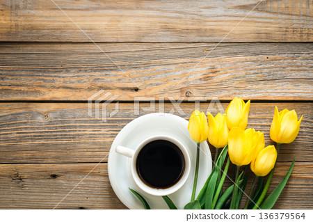Bouquet of yellow tulips and cup of coffee on a wooden background, top view. Bouquet of yellow tulips and cup of coffee on a wooden background, top view. 136379564