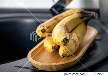 A bunch of ripe yellow bananas in the kitchen near the sink. A bunch of ripe yellow bananas in the kitchen near the sink. 136379596