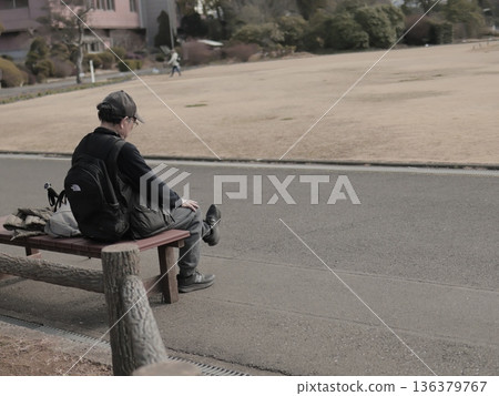 一位老人在大型公園的長椅上休息。 136379767