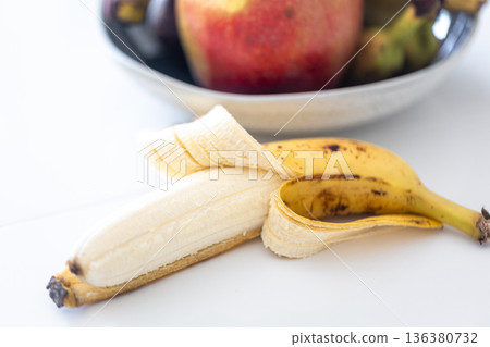 An open banana and a plate of fruit on the kitchen table. An open banana and a plate of fruit on the kitchen table. 136380732