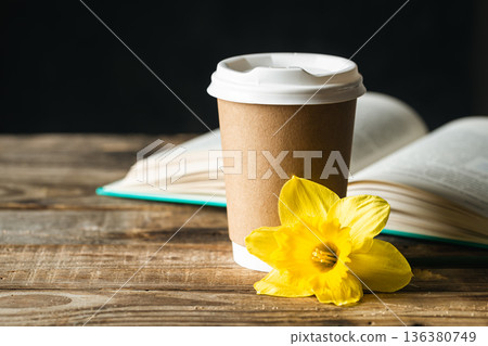 Paper cup, book and yellow flower on a blurred wooden background. 136380749