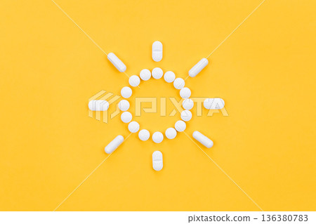 Pills in the shape of the sun, on a yellow background, flat lay. Pills in the shape of the sun, on a yellow background, flat lay. 136380783