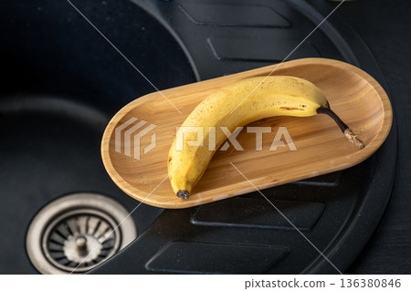Ripe yellow banana in the kitchen near the sink. 136380846