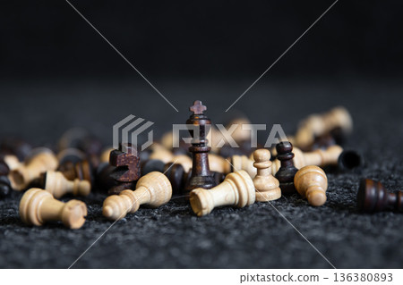 Scattered chess pieces on a blurred black background. Scattered chess pieces on a blurred black background. 136380893