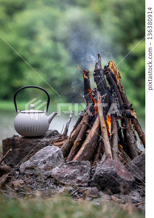 Small kettle is heated on a bonfire, outdoor recreation concept. 136380914